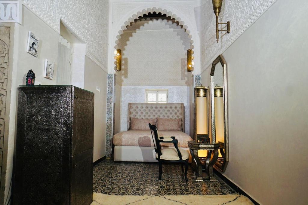 a bedroom with a bed and a chair and a table at Riad Amelia : Lalla Nora Room in Tetouan