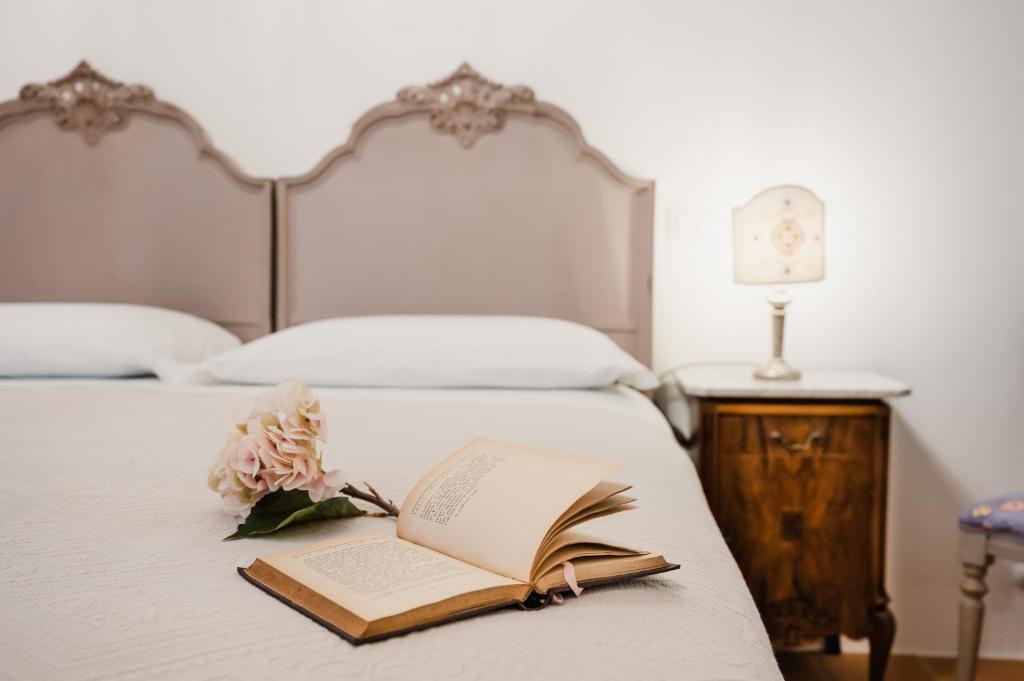 un letto con un libro aperto e un fiore sopra di Locanda Mescoglia a Corciano