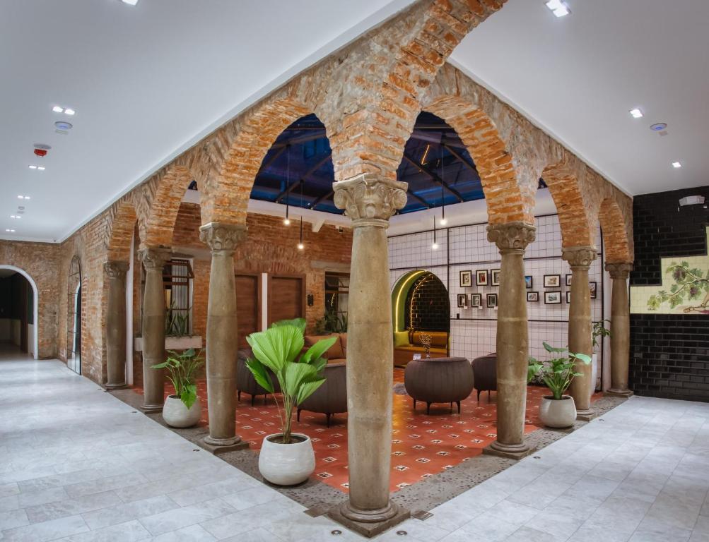 eine Lobby eines Gebäudes mit Säulen und Stühlen in der Unterkunft Wanderlot - Hotel Plaza Central in Riobamba