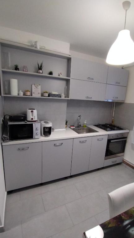 una cucina con armadi bianchi e lavandino di Ana Apartament a Râmnicu Vâlcea