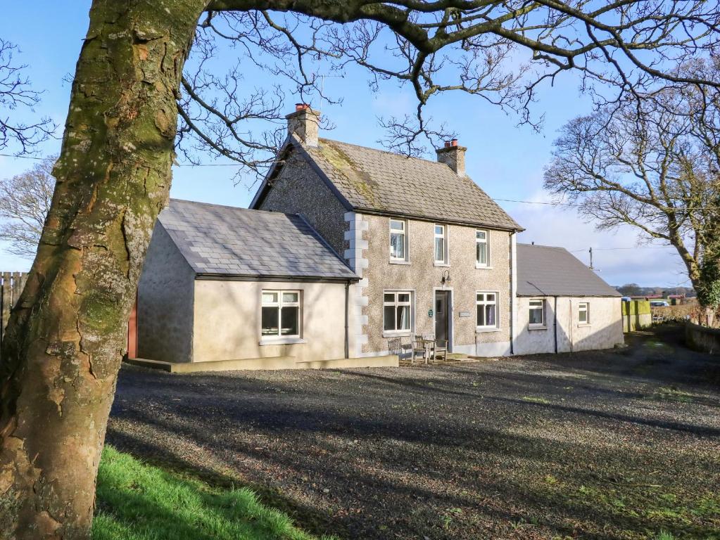 ein altes Haus mit einem Baum davor in der Unterkunft Rosies Cottage in Bushmills
