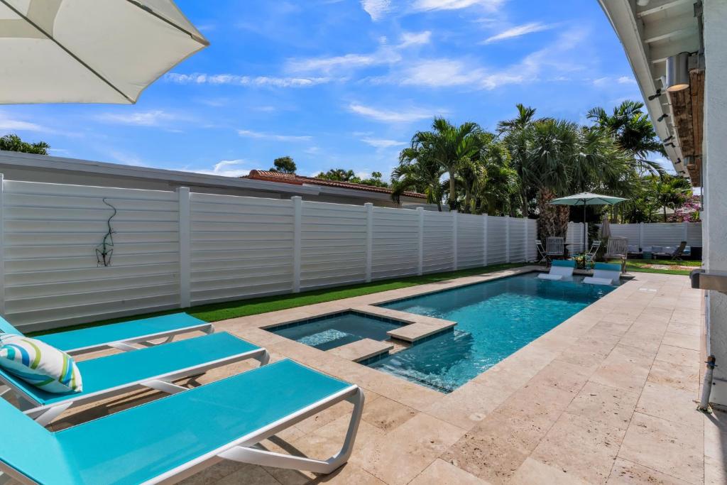 uma piscina com duas espreguiçadeiras e um guarda-sol em Sandcastles & Sunshine at Towering Palms of Wilton Manors residence em Fort Lauderdale
