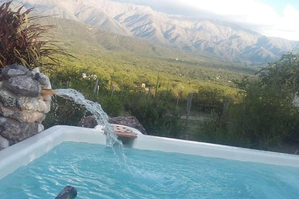 una piscina con una fuente de agua con montañas en el fondo en bellos atardeceres en Villa Las Rosas