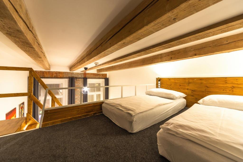 two beds in a room with wooden ceilings at S42 Hotel Prague in Prague