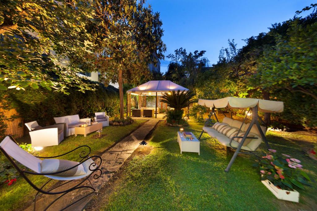einen Garten mit weißen Möbeln und einem Sonnenschirm in der Unterkunft AMORE RENTALS - Maison De Charme in Sorrent