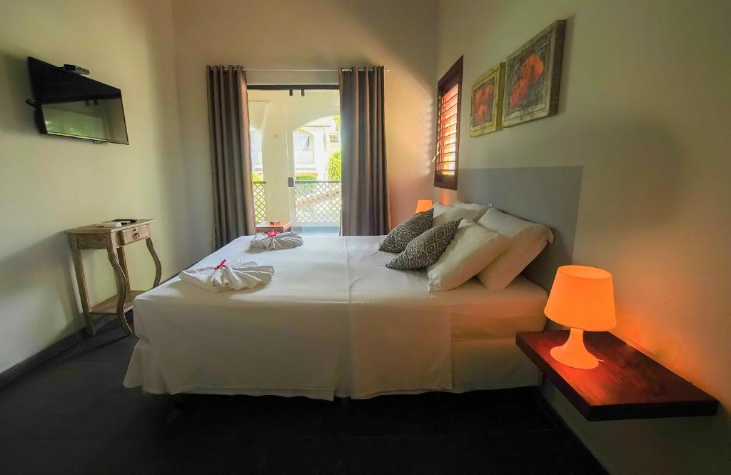 a bedroom with a large white bed with a lamp at Flor da Mata in Pipa