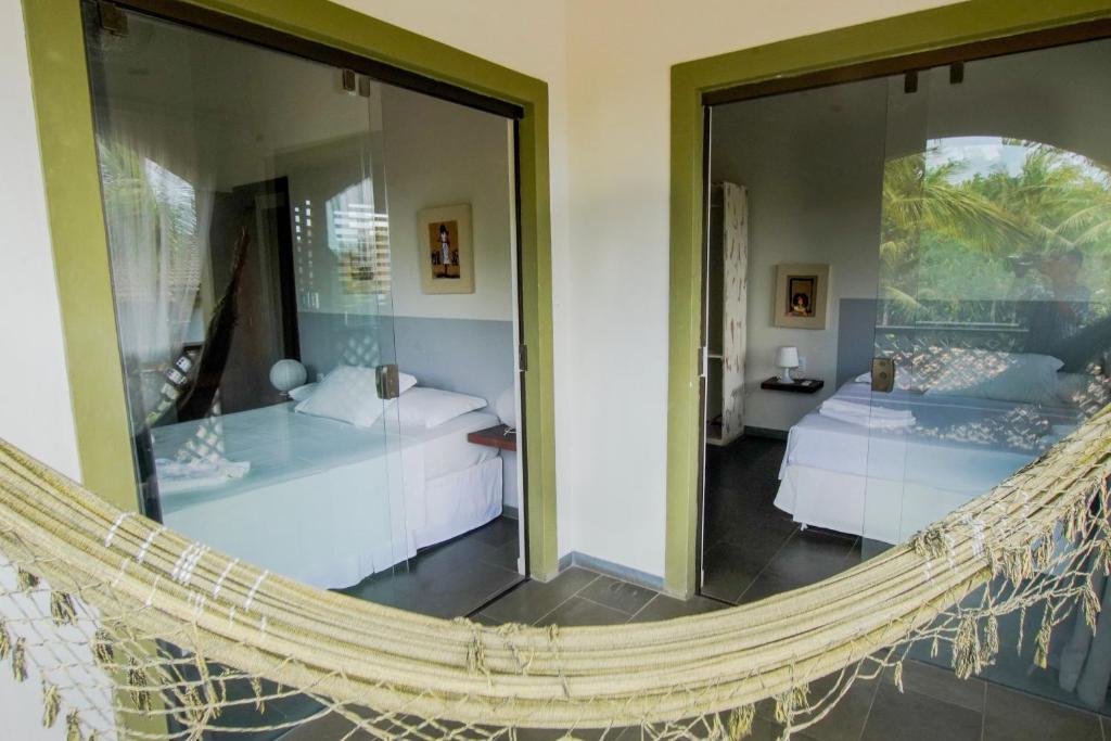a hammock in a hotel room with two beds at Flor da Mata in Pipa