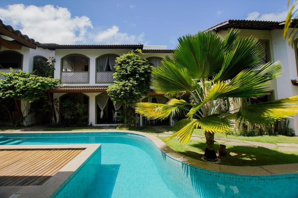 a swimming pool in front of a house with a palm tree at Flor da Mata in Pipa