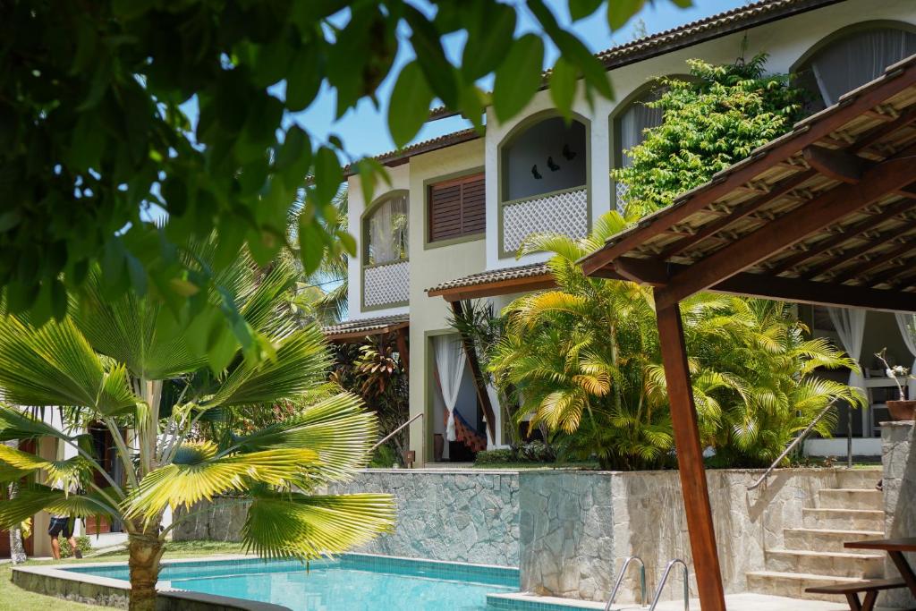 a house with a swimming pool and palm trees at Flor da Mata in Pipa