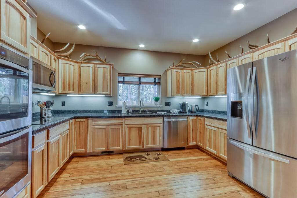 a kitchen with wooden cabinets and a stainless steel refrigerator at Spacious Three Rivers Lodge✦Fenced .5 Acre✦Hot Tub in Bend