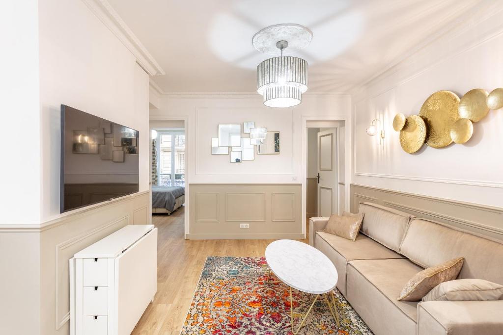 a living room with a couch and a tv at SUITE RAPHAEL Tour Eiffel in Paris