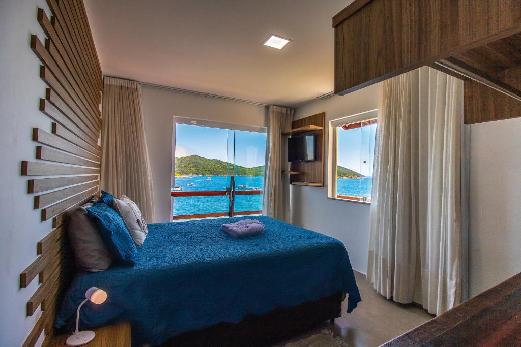 sypialnia z niebieskim łóżkiem i widokiem na ocean w obiekcie Villa Orion w mieście Arraial do Cabo