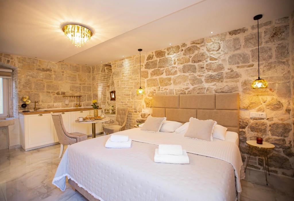 1 dormitorio con 1 cama grande y pared de piedra en Guest House Paradise en Split