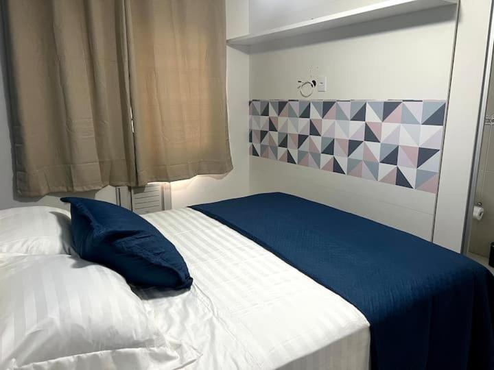 ein Schlafzimmer mit einem Bett mit einem blauen Kissen in der Unterkunft Apto Vista Mar Varanda Gourmet in Praia Grande