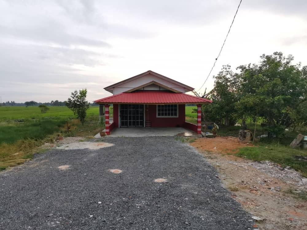 ein kleines rotes Gebäude mit rotem Dach auf einem Feld in der Unterkunft HomeStay Abah Alor Pongsu 