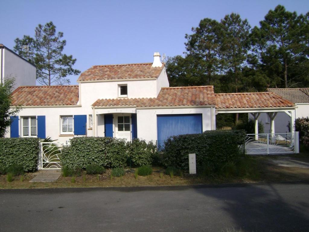 une maison blanche avec un garage bleu dans l'établissement Maison La Tranche-sur-Mer, 5 pièces, 6 personnes - FR-1-476-77, à La Tranche-sur-Mer