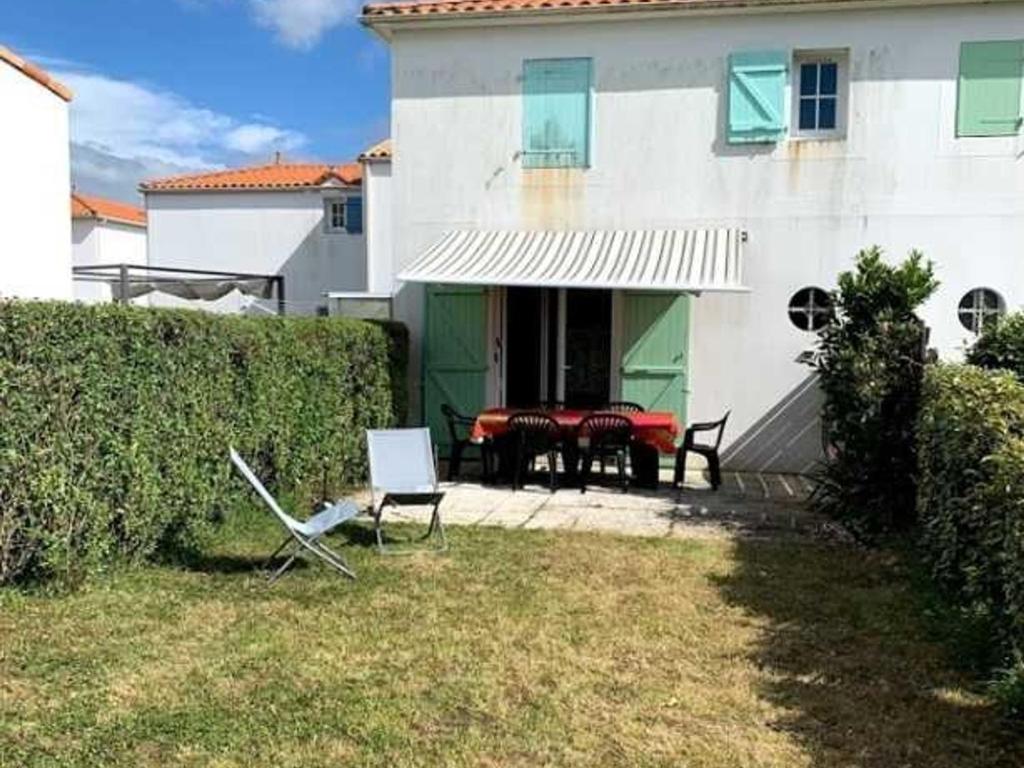une maison avec une table et des chaises dans la cour dans l'établissement Maisonnette 5 personnes avec piscine et parking - FR-1-476-170, à La Faute-sur-Mer