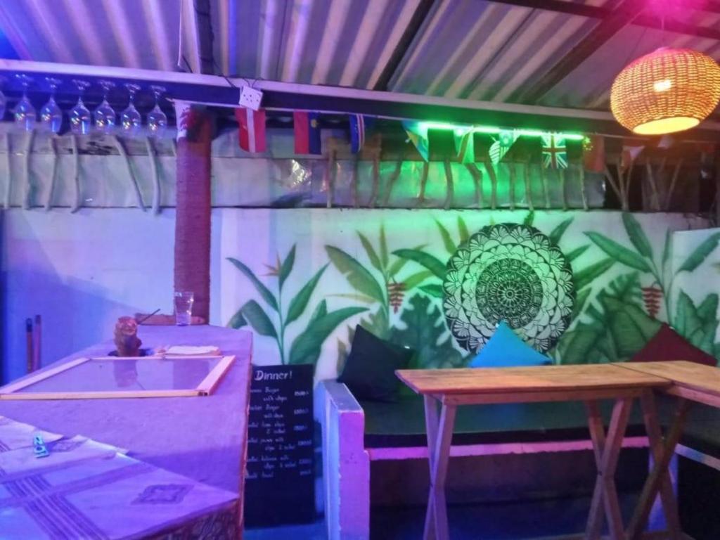 a restaurant with a table and a wall with plants at Hostel Taru surf camp and restaurant in Unawatuna