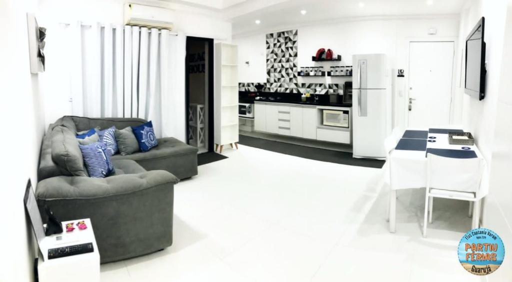 a living room with a chair and a kitchen at Flat Capitania em Pitangueiras perto da praia in Guarujá