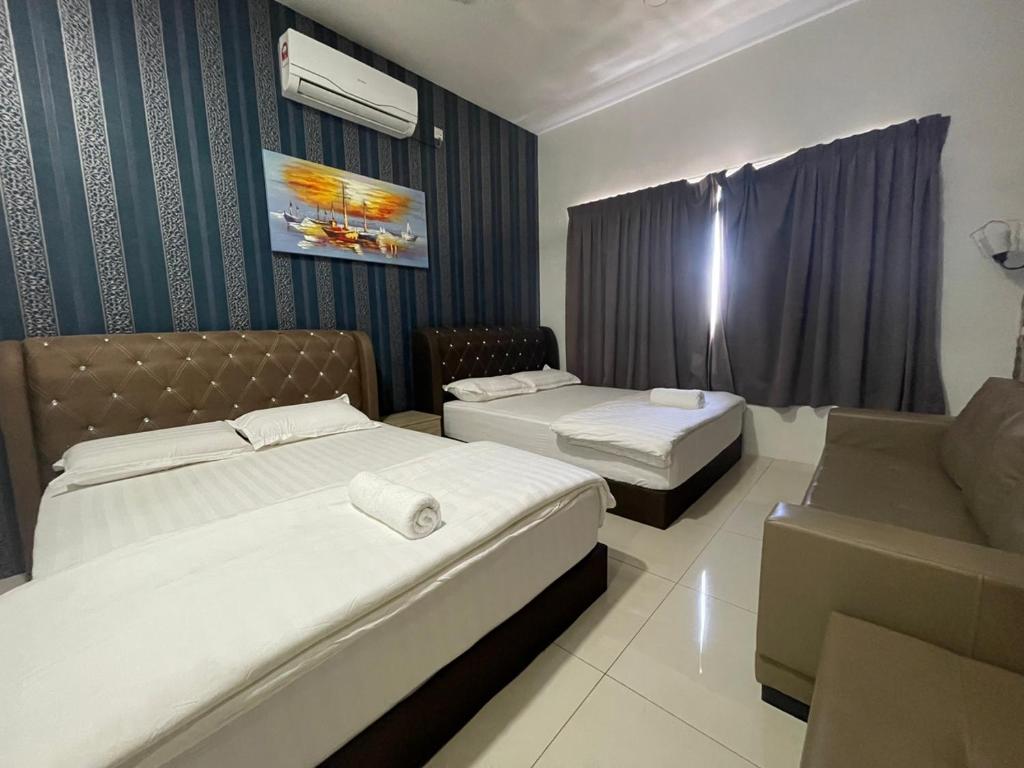 a hotel room with two beds and a couch at Sunny Seaview@Icon Residence in Kuala Terengganu
