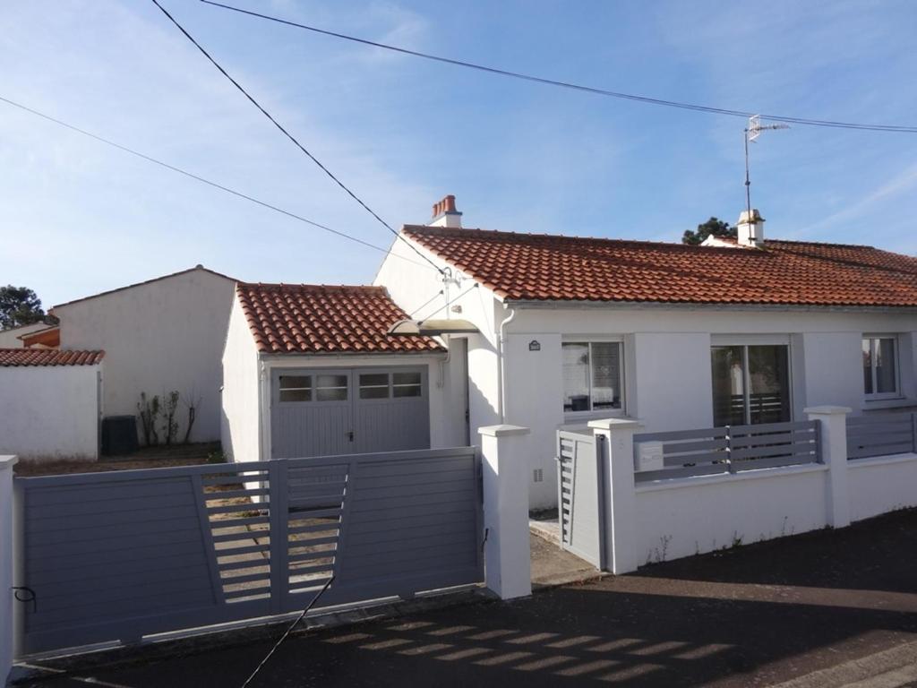 a white house with a gate and a fence at Maison confortable près de la plage, au calme, idéale pour des vacances en famille - FR-1-476-101 in La Faute-sur-Mer
