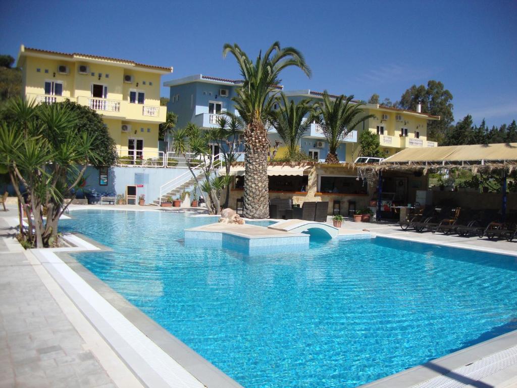 una gran piscina con palmeras y edificios en Meraki Apartments and Studios, en Tolo