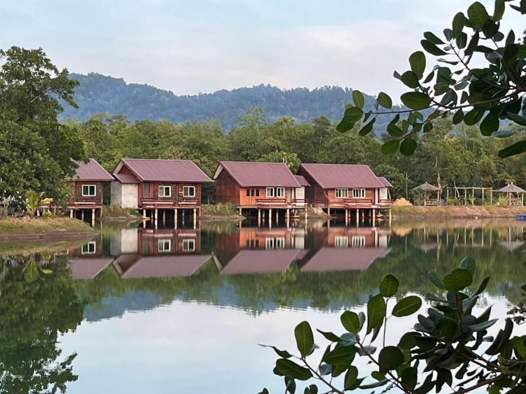a row of houses on a lake with trees at Bungalow Together in Ban Khanim