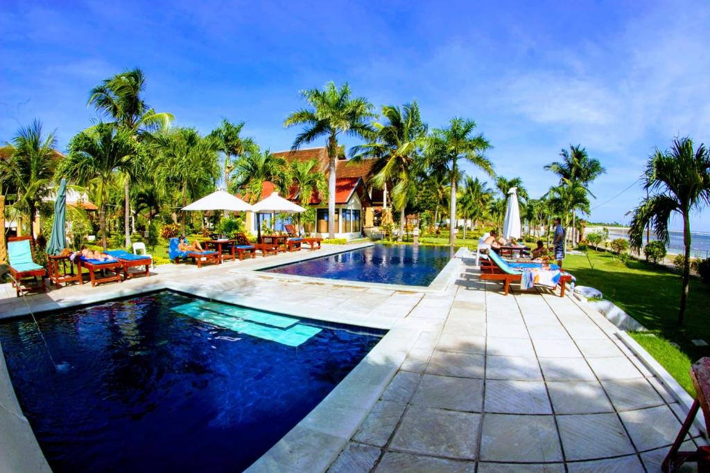 una piscina con sillas y sombrillas en un complejo en Aman Gati Hotel Lakey, en Huu