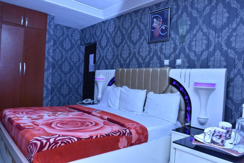 a bedroom with a large bed with a red blanket at World Class Hotel & Apartments in Abuja