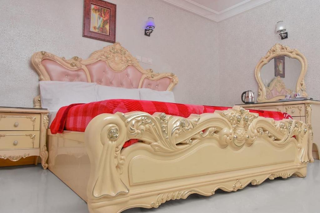 a bedroom with a gold bed with a red blanket at World Class Hotel & Apartments in Abuja