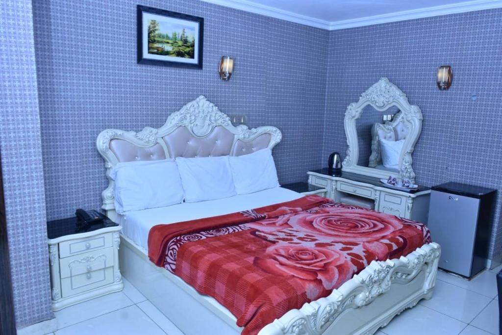 a bedroom with a white bed with a red blanket at World Class Hotel & Apartments in Abuja