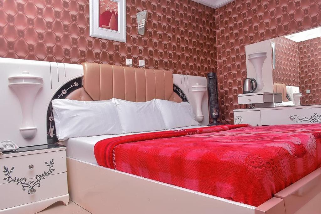 a bedroom with a large bed with a red blanket at World Class Hotel & Apartments in Abuja
