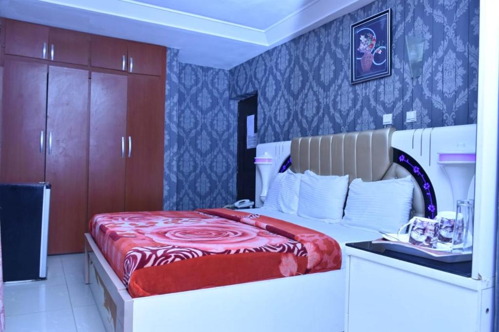 a bedroom with a bed with a red blanket on it at World Class Hotel & Apartments in Abuja