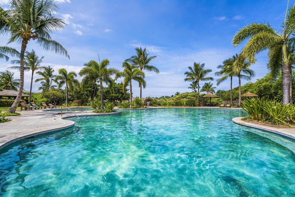a large pool with palm trees in a resort at Kulalani 2003 townhouse in Waikoloa