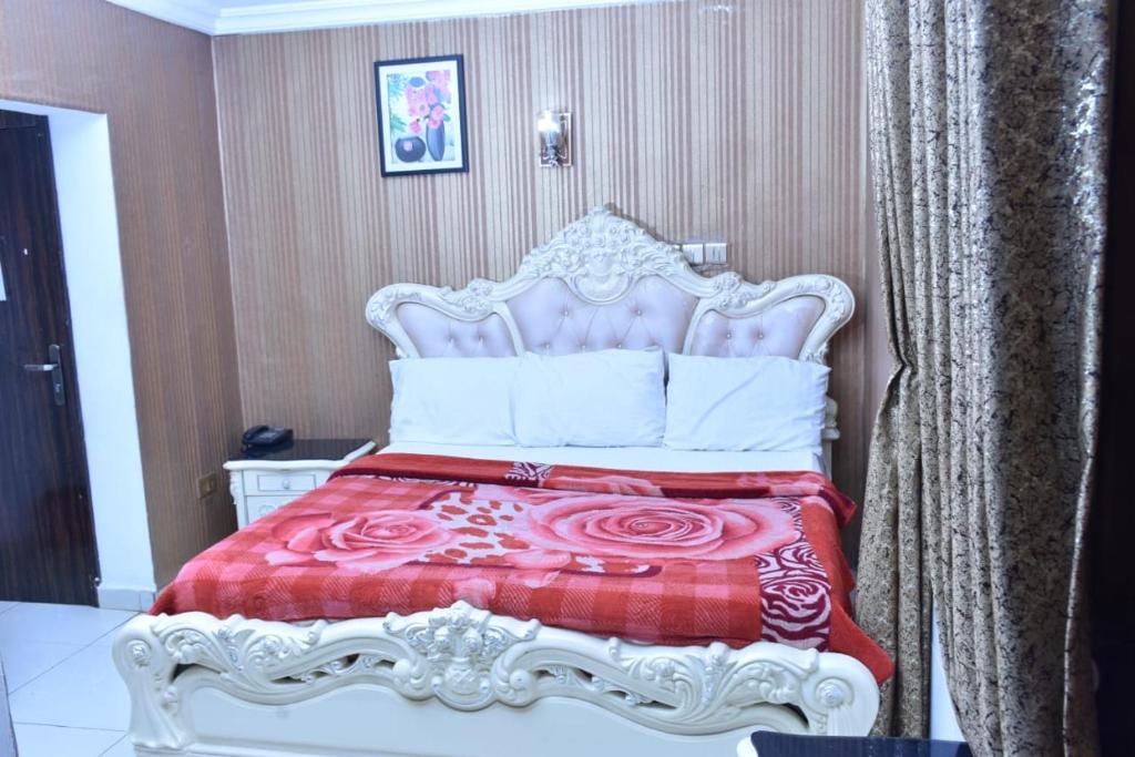 a bedroom with a bed with a red and white bedspread at World Class Hotel & Apartments in Abuja