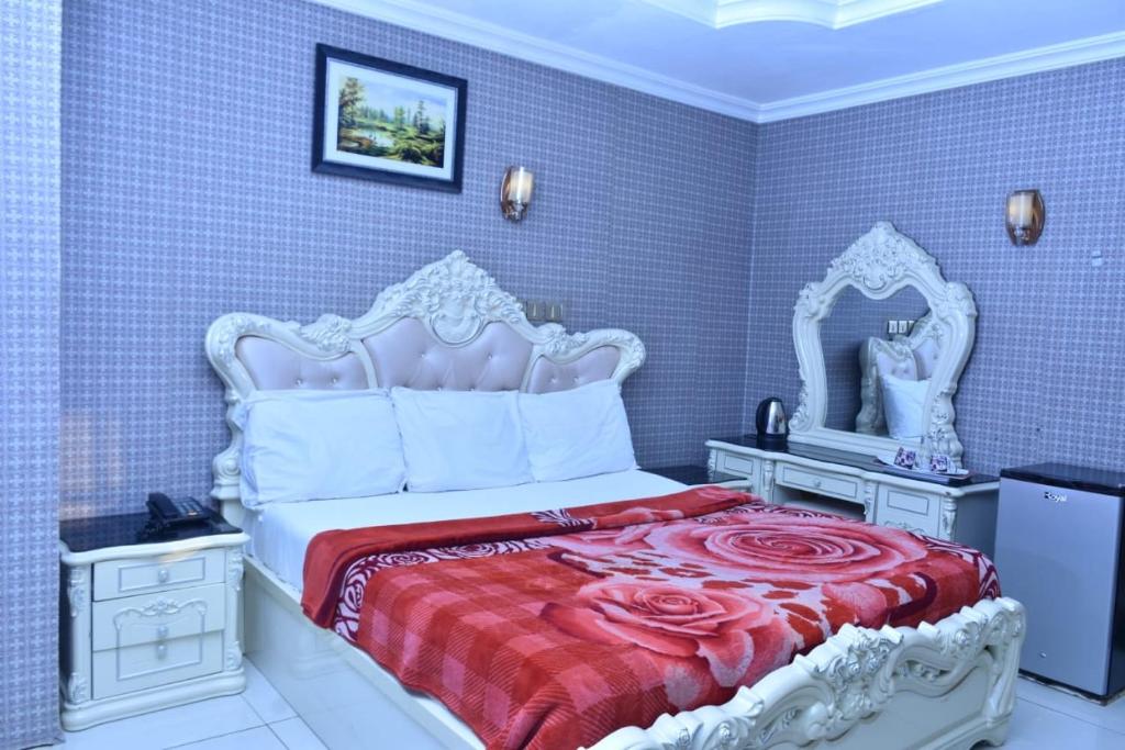 a bedroom with a white bed with a red bedspread at World Class Hotel & Apartments in Abuja