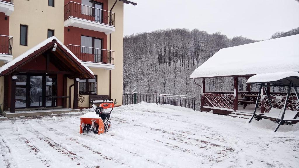 a snow bike parked outside of a building in the snow at Pensiunea 7 Brazi II in Poiana Mărului