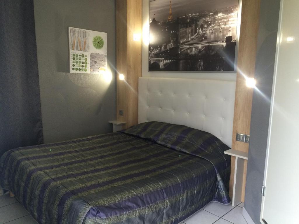 Initial by balladins Lyon / Chanas في شناس: غرفة نوم صغيرة بسرير وبطانية مخططة