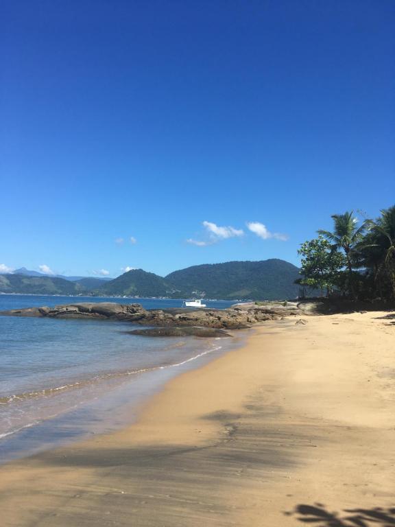 uma praia arenosa com palmeiras e o oceano em Casa pé na areia na Praia de Fora - Ponta Leste - Angra dos Reis em Angra dos Reis
