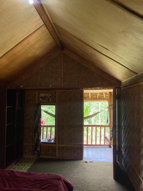 an attic room with a wooden ceiling and two windows at Tetebatu Sama Sama Bungalows in Tetebatu