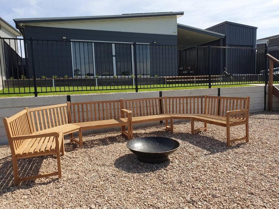 two wooden benches and a fire pit in front of a building at Olley's Place in Wellington East