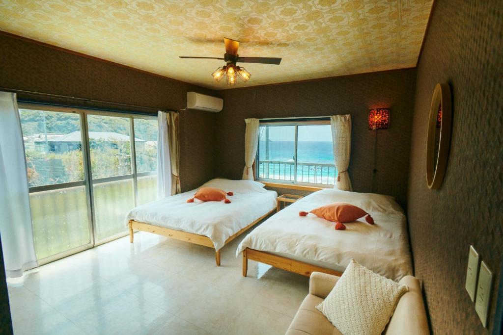 two beds in a room with a view of the ocean at Vacation House Familia in Kōzushima