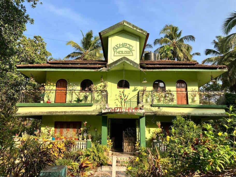a green house with a balcony on top of it at Ashpil House Guest House Margao South Goa in Navelim