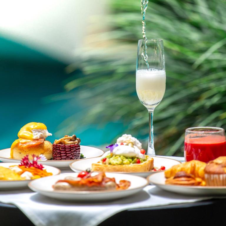 A styled breakfast spread with pastries, savoury plates, fruit juice and a tall glass of milk.