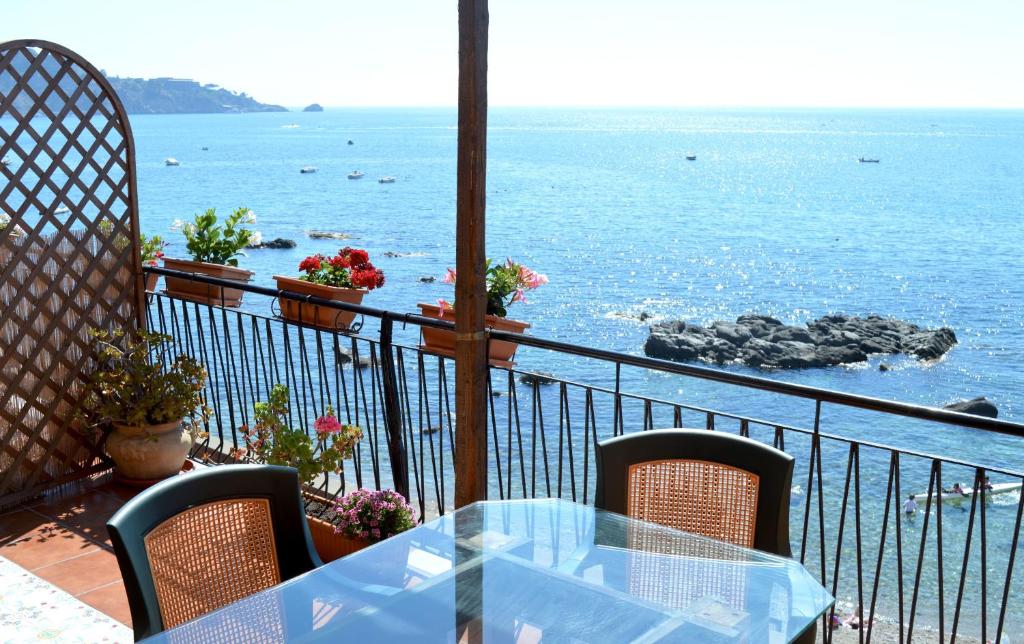 a table and chairs on a balcony overlooking the ocean at Teocle Beach rooms in Giardini Naxos