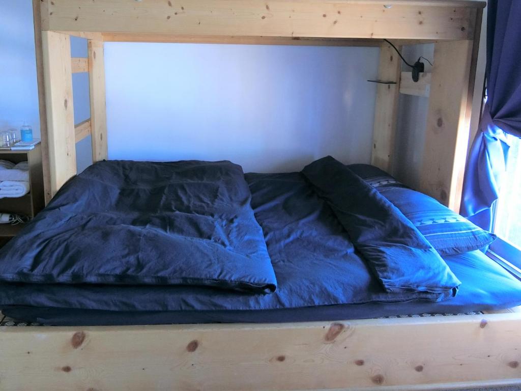 a wooden bunk bed with blue sheets and pillows on it at Shirokuma Inn in Toyama