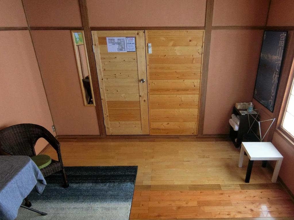 a room with a wooden door and a room with a bed at Shirokuma Inn in Toyama