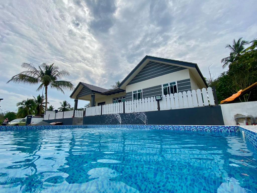 a house with a swimming pool in front of a house at Homestay Bendang Hilir in Kuala Nerang