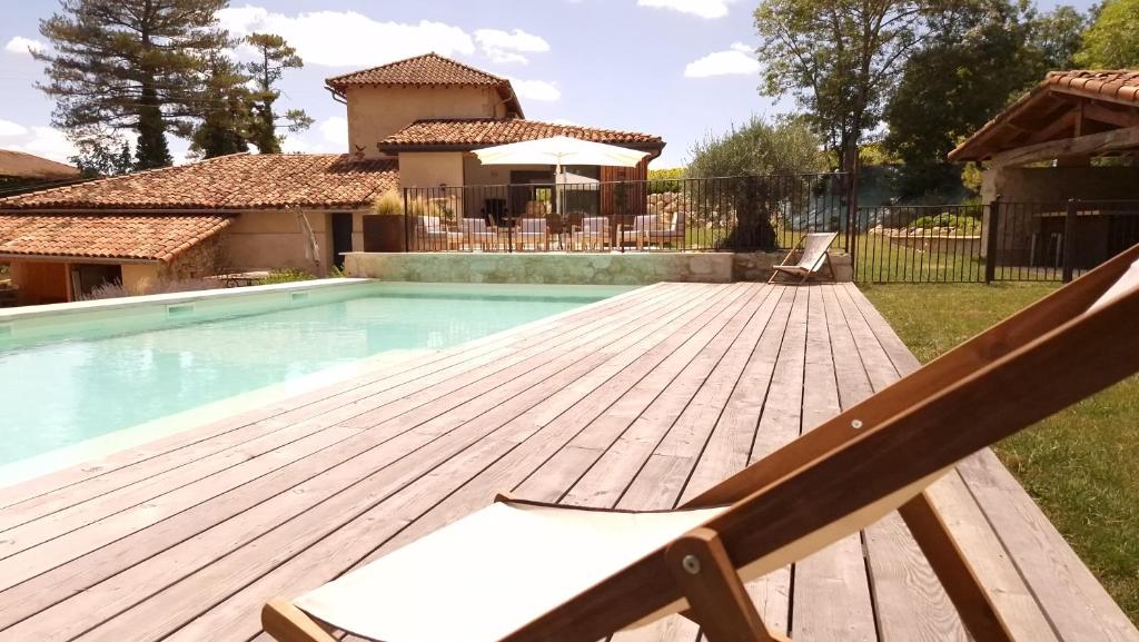 uma piscina com um deque de madeira ao lado de uma casa em Barbarens Maison d'hotes em Castelnau-Barbarens