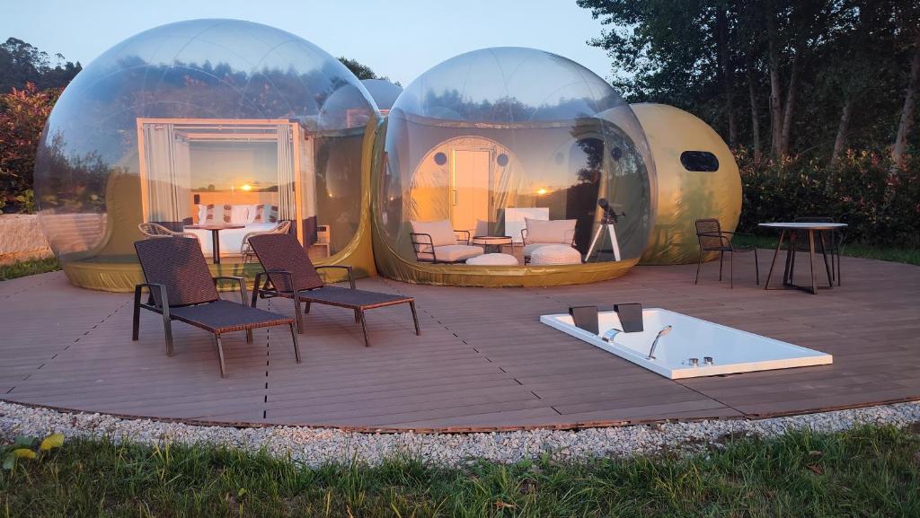 un grupo de cúpulas de cristal con sillas y mesa en Luzada - Glamping Burbujas Galicia en Juances